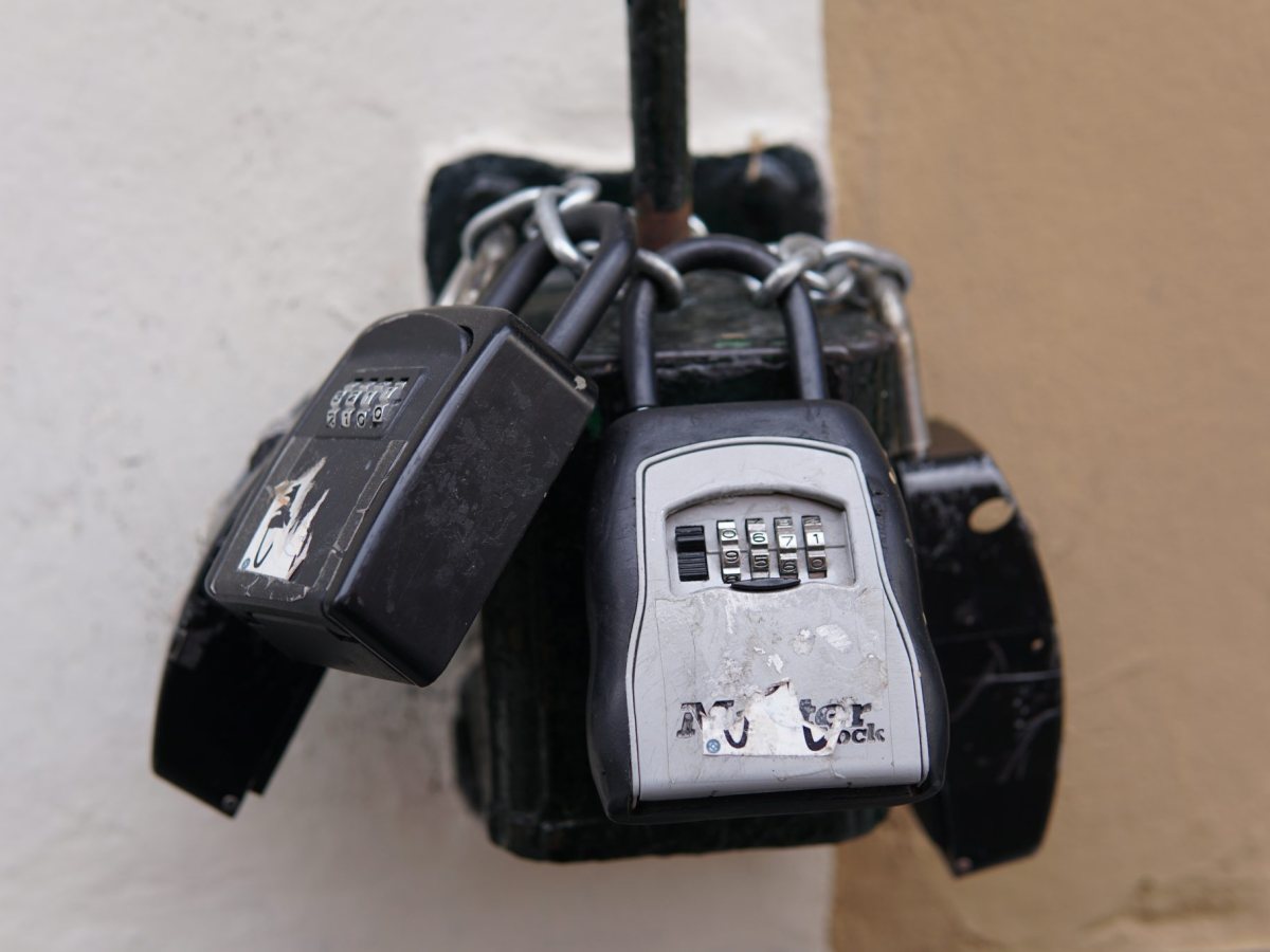 Three combination padlocks on a chain around a metal box