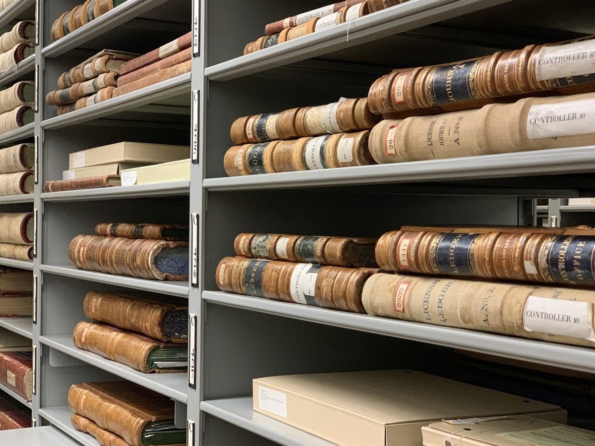 Shelves of an archive filled with old bound record books. Rayonnages d’archives remplis de vieux registres reliés.
