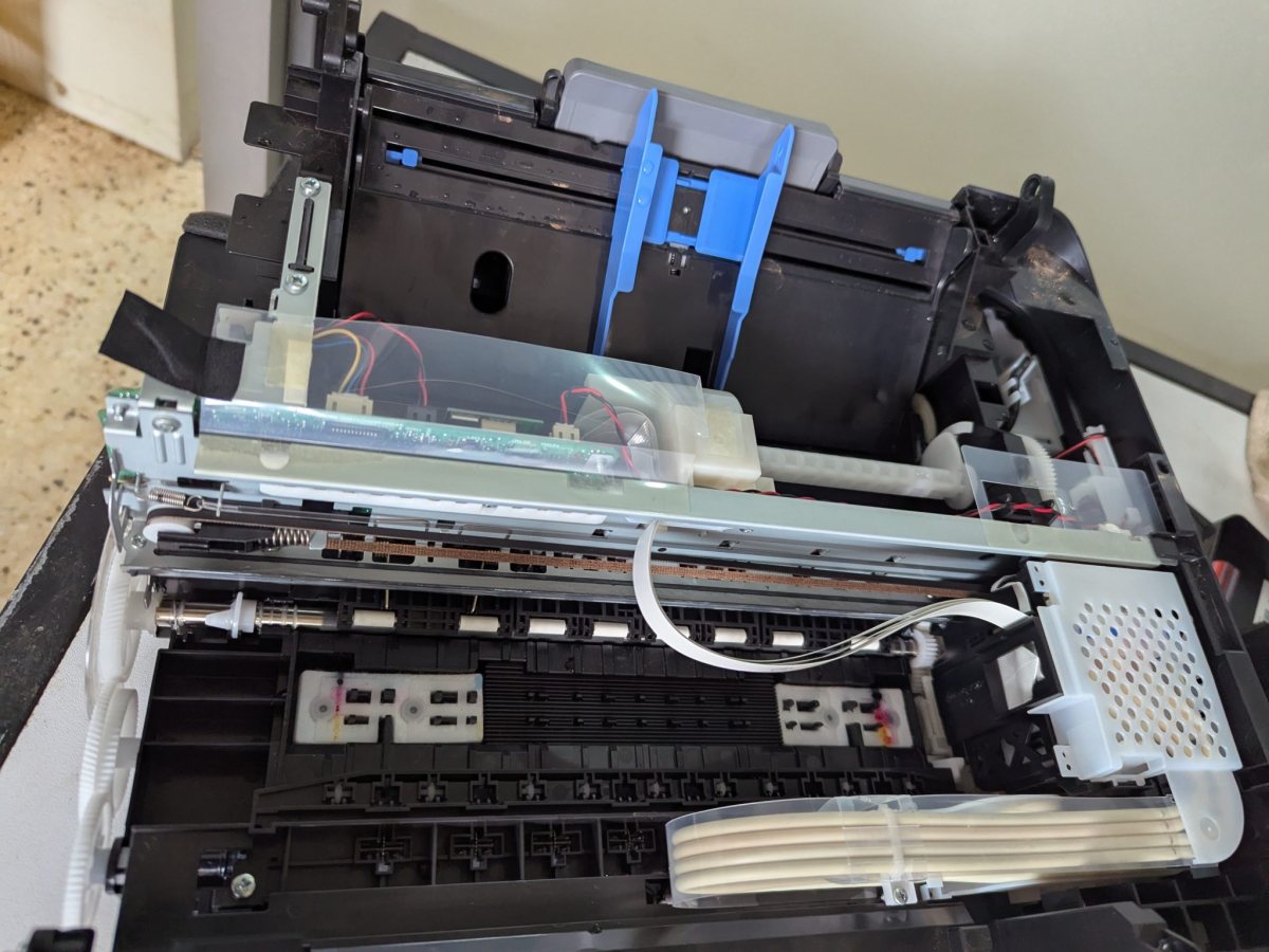 The opened inside of an office printer with gears, rollers and cables Osoba za stolom uspoređuje ispisani popis narudžbi s brojkama na zaslonu.