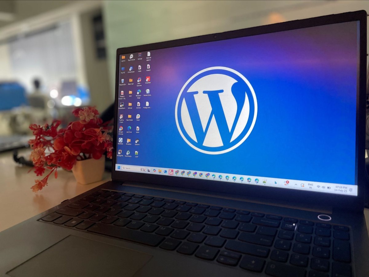 A laptop on an office desk showing the WordPress logo, with a small plant beside it Un ordinateur portable sur un bureau affiche le tableau de bord d’un site web, un carnet posé à côté.